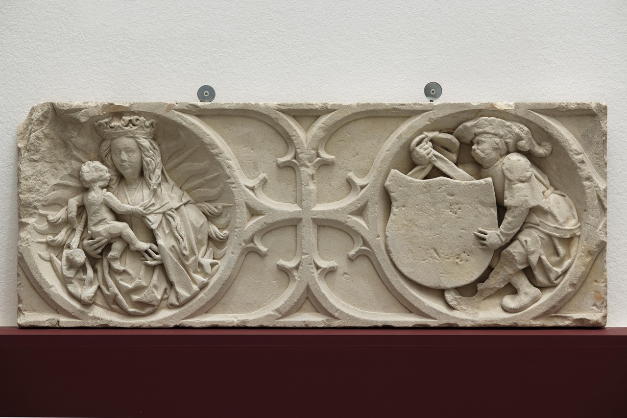 Fragment van schoorsteenfries met Maria met Kind , omhangen met een rozenkrans met gebedsnoot, en een wapendragende soldaat
