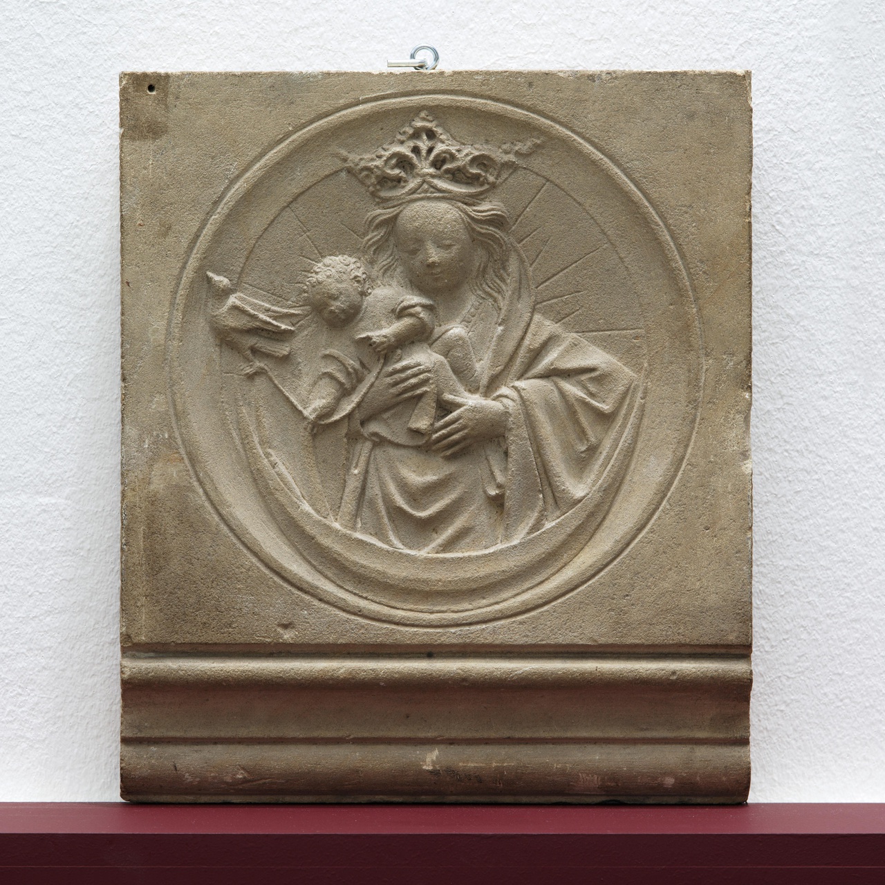 Fragment van een schoorsteenfries met voorstelling van Maria met Kind, dat speelt met een vogel