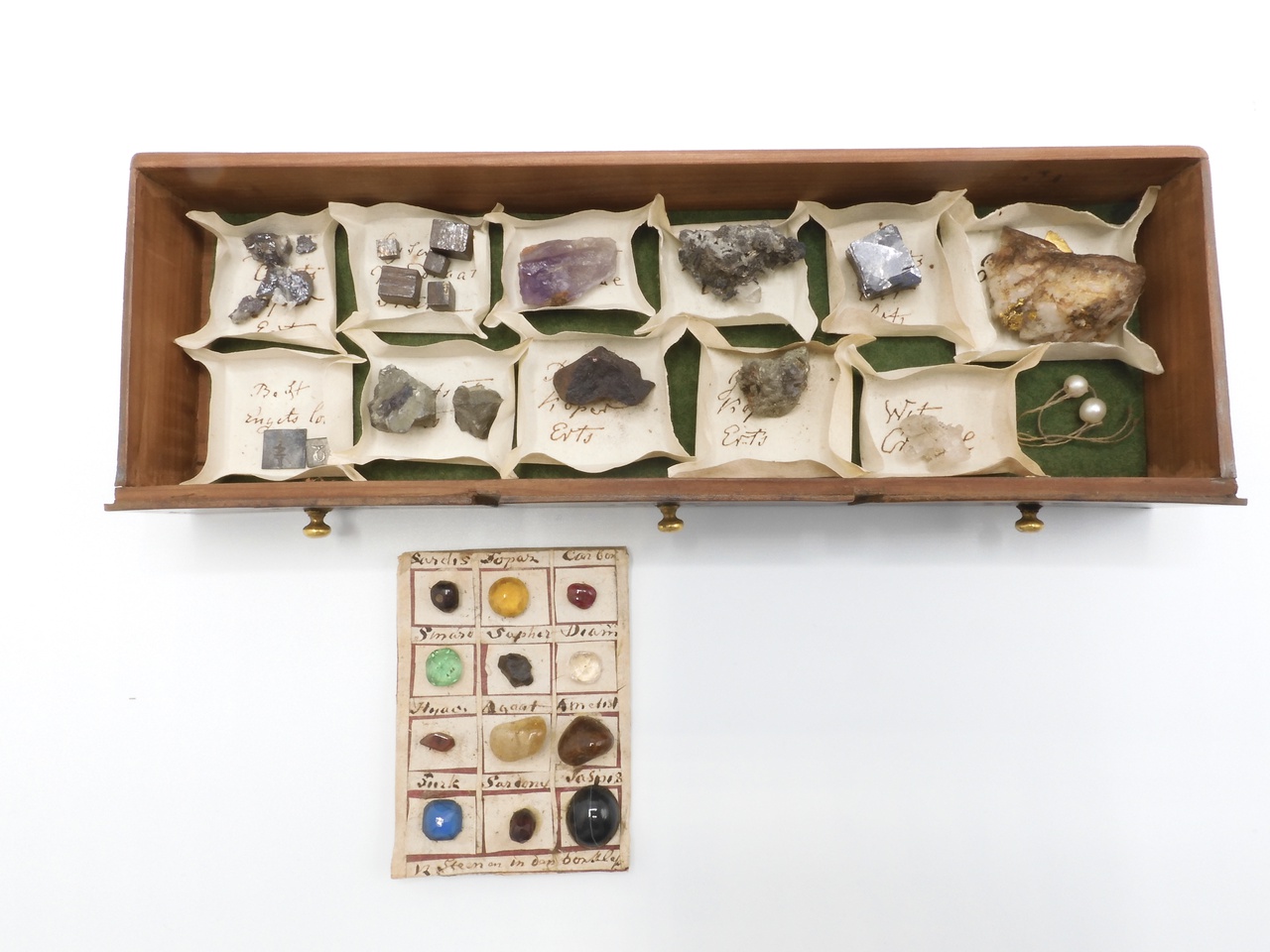 Verzameling ertsen, mineralen en twee parels gelegen in papieren bakjes met opschrift, en een borstlap met twaalf edelstenen.