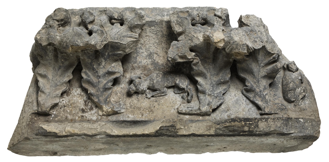 Gebeeldhouwde gootlijst, fragmenten met krulbladeren, waartussen een zittend en een springend dier en Sint Joris met de draak