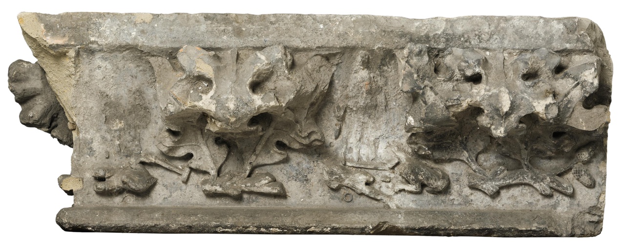 Gebeeldhouwde gootlijst, fragment met krulbladeren, waartussen een liggende man en een staande vrouw met twee liggende figuren