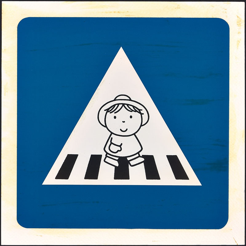 verkeersbord [met een afbeelding uit het kinderboek: 'ik kan alleen op straat', voorloper van kinderboek: 'stoeprand ... stop!', met kind met hoedje dat loopt op het zebrapad op p. 23]