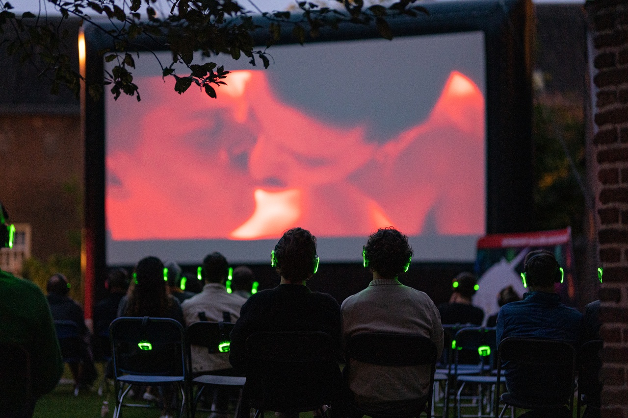 Filmvoorstelling in de tuin van het museum, met groot scherm en bezoekers tijdens het Queer Film Festival in 2022